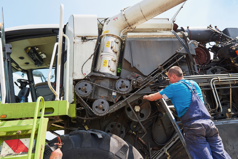 Mechanik serwisujący silnik kombajnu podczas prac polowych